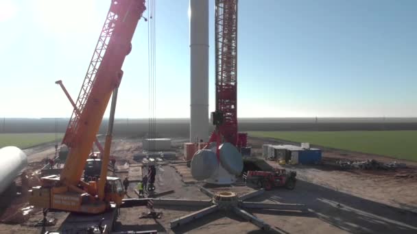 建設中の風力発電タワー工場の建設プロセス クレーンリフトローター ローターの設置 クリーン 再生可能エネルギー 空中映像 — ストック動画