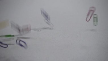 Çok renkli klipsler masaya düşer. Ofis kavramı. Slow Motion 250 fps. İzole edilmiş beyaz arkaplan