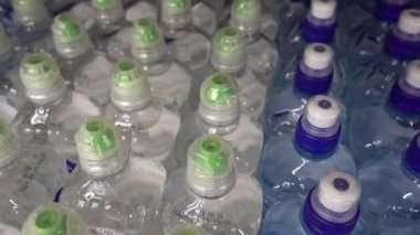 Plastik şişeler, su, kapaklar, içecekler. Kamera hareket halinde üst görünümde