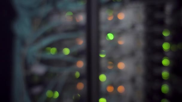 Blinking orange and green indicators on network switch back panel. Blurred server rack. — Stock Video