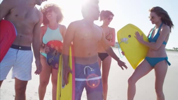 Amigos sosteniendo tablas de cuerpo junto al océano — Vídeo de stock