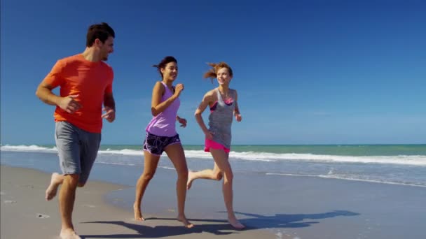 Male and females jogging on beach — Stock Video