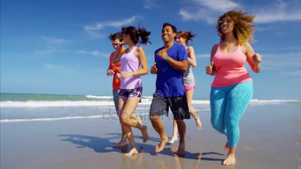 Друзья, поддерживающие форму на пляже — стоковое видео