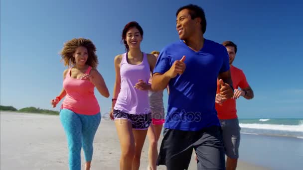 Mannetjes en vrouwtjes joggen op strand — Stockvideo