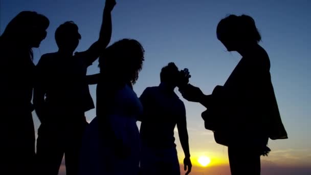 Vänner njuter av solnedgången på stranden — Stockvideo