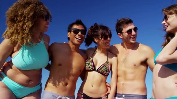 Machos y hembras divirtiéndose en la playa — Vídeo de stock