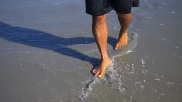 Человек ходит босиком по пляжу — стоковое видео