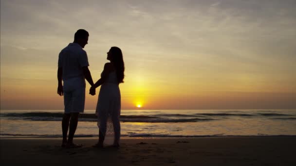 Par njuter av solnedgången på stranden — Stockvideo