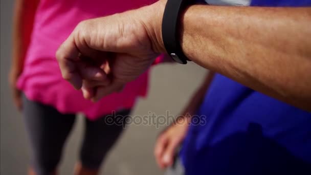 Пожилые люди, использующие спортивные часы — стоковое видео