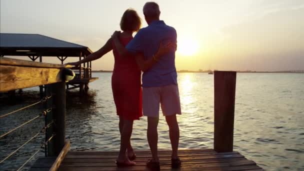 Casal desfrutando do pôr do sol no cais — Vídeo de Stock