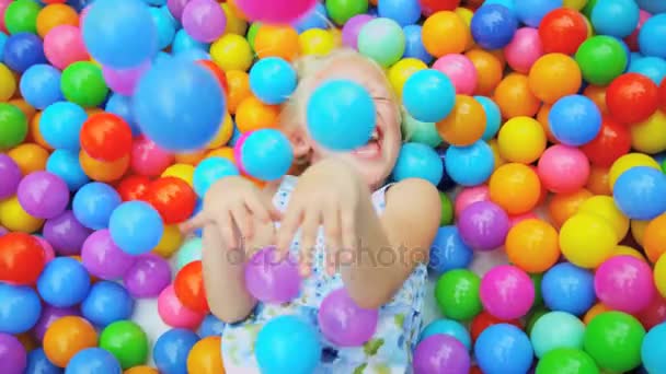 Chica jugando en piscina lleno bolas — Vídeo de stock
