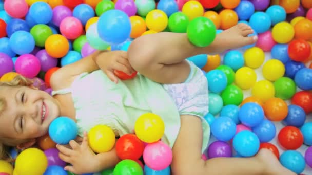 Chica sentada en bolas en piscina infantil — Vídeo de stock