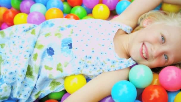 Chica cubierta de bolas en piscina infantil — Vídeos de Stock