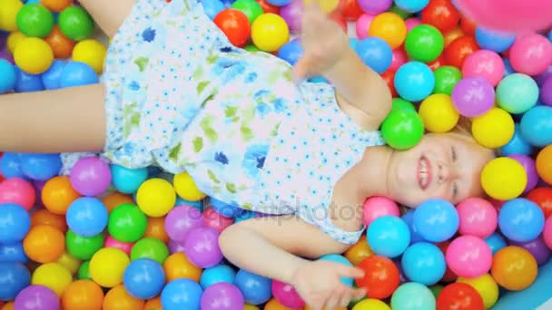 Ребенок, покрытый мячами в бассейне — стоковое видео