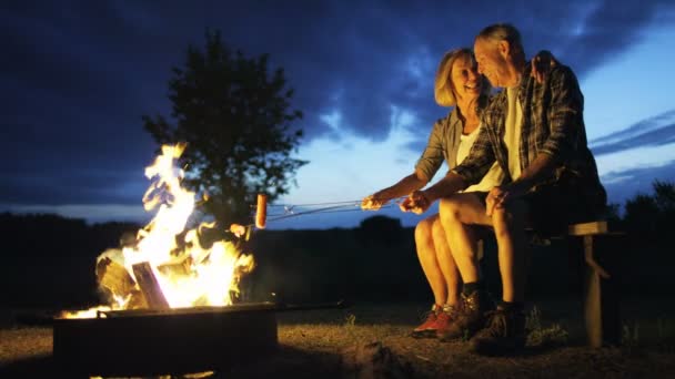 Paar koken worst boven een kampvuur — Stockvideo