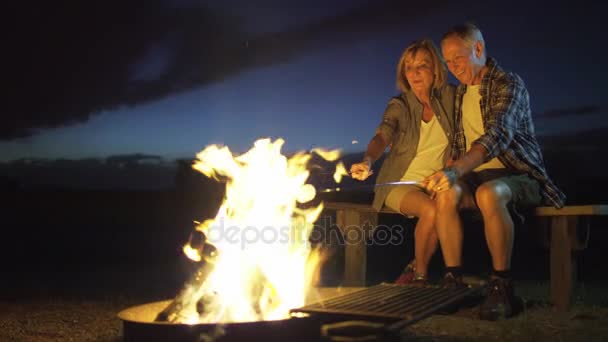 キャンプファイヤーでマシュマロを焼くことのカップル — ストック動画