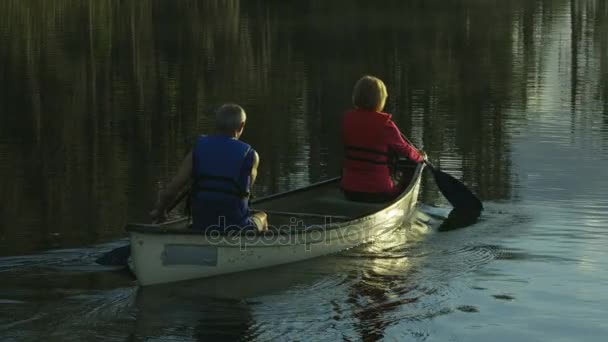 Пожилые люди катаются на каяке по озеру — стоковое видео