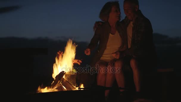 Pareja cocinar salchichas sobre una fogata — Vídeos de Stock