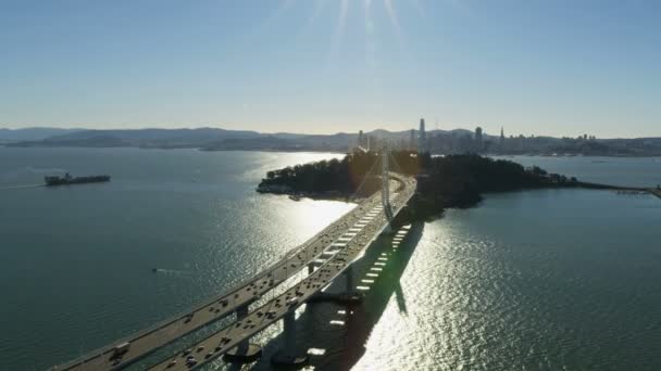 オークランド湾道路交通橋サンフランシスコ市高層ビル コンテナー船宝の島カリフォルニア アメリカ近くの日光の下で空撮 — ストック動画