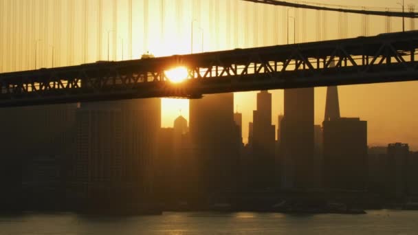 オークランド湾ダブル デッキ道路橋通勤車両交通私たち 高速道路サンフランシスコの港市高層ビル アメリカ カリフォルニアの夕日空撮 — ストック動画
