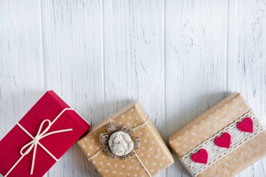 Üç hediye, açık ahşap arka planda fotokopi alanı olan bir yere yakın duruyor. Kutular dolusu hediye içeren metin çerçevesi. Satış afişi, indirimi, indirimi için arka plan.