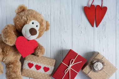 Doğum günü kartı, anneler günü, sevgililer günü. Kalpli oyuncak ayı, açık tahta arka planda hediye kutuları. Yukarıdan görüntüle