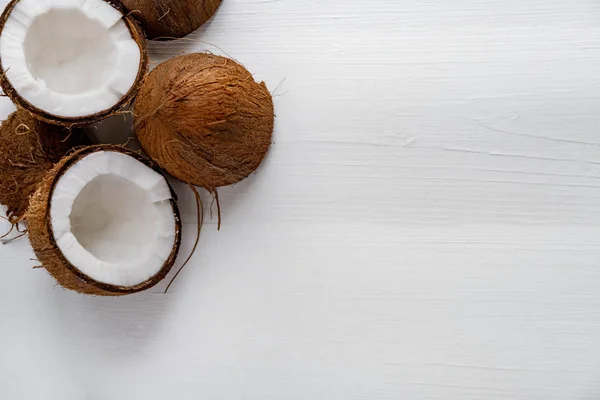 Hälften hackad kokosnöt på en vit trä bakgrund. Tropisk bakgrund med plats för kopieringsutrymme. Utsikt ovanifrån — Stockfoto