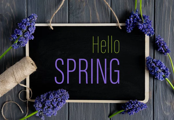 Bonjour Spring. Félicitations lettrage lumineux sur un fond en bois gris foncé avec des fleurs lilas printemps. Carte postale Kraft sur un thème printanier — Photo