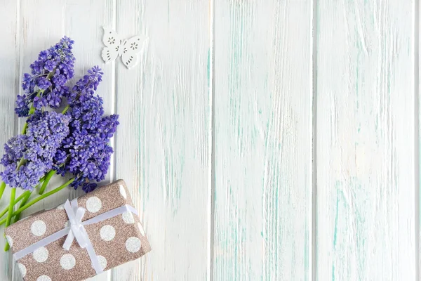 Spring flowers of lilac color with a gift box on a light wooden background. Greeting card with spring flowers. View from above — Stockfoto