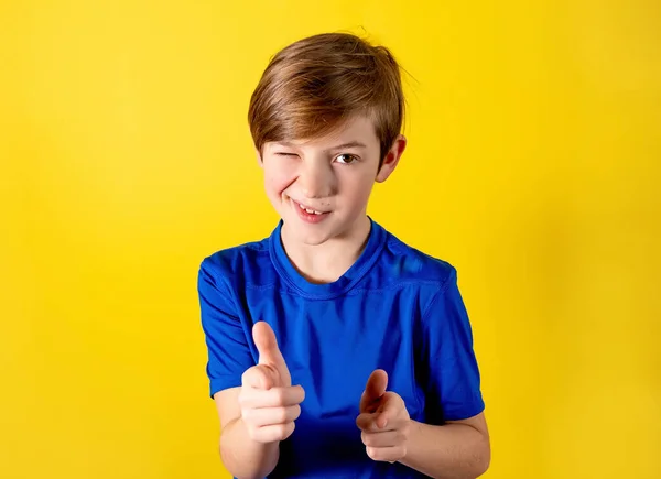 Close up boy winks. Hey, you. 9 years old boy winks with a smile. Photo of a boy on an orange background for the holiday, stock, sale