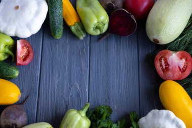 Arka planda sebzeler, salatalıklar, domatesler, kabaklar, kabaklar, tatlı biberler. Merkezinde sebze çerçevesi olan bir yazıt için bir arka plan.