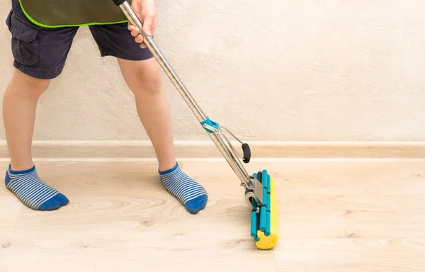 Limpieza de la casa durante el período de cuarentena. Ayude a los niños a limpiar el apartamento, en casa. Un niño trapea pisos — Foto de Stock