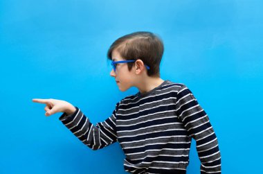 Gözlüklü çocuk, kendi tarafından yakından çekilmiş, bir şeyi işaret ediyor. Neşeli şirin çocuk elini gösteriyor.