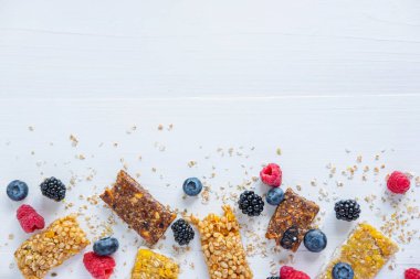 Arka planda ahududu, yaban mersini ve böğürtlen olan enerji barları. Sağlıklı diyet yemekleri. Beyin aktivitesini desteklemek için sabahları besin.