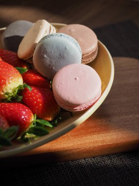 Farklı renklerde renkli badem kurabiyeleri, mandalina, çilek, tatlı yemek ve meyve.