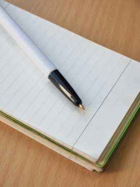 Beyaz defter ve siyah tükenmez kalem.