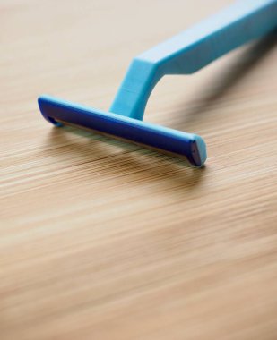 Ahşap arka planı olan tek kullanımlık mavi jilet.