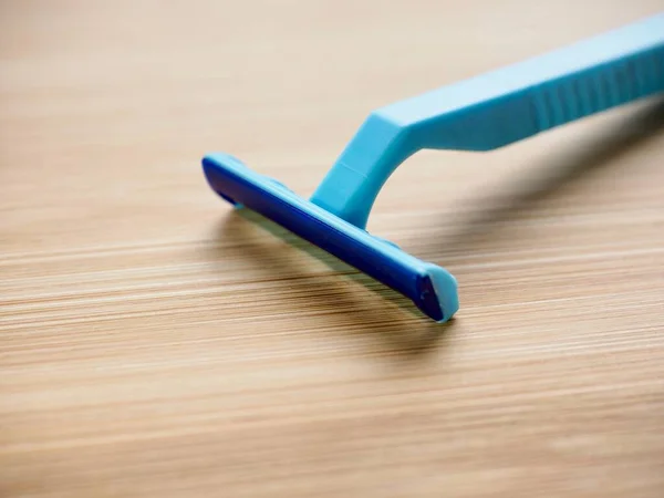Blue disposable razor with wooden background