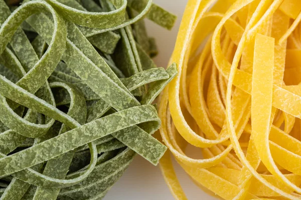 Uncooked tagliatelle pasta, green and yellow, two nests
