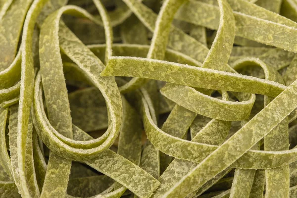 Uncooked green tagliatelle pasta, one nest, macro close up