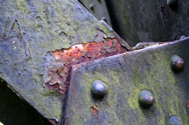 Eski perçinlenmiş ve yıpranmış çelik plakalar.