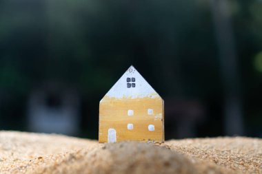 Güneş ışığı arka plan ile yeşil çim üzerinde küçük ev modeli kapalı.