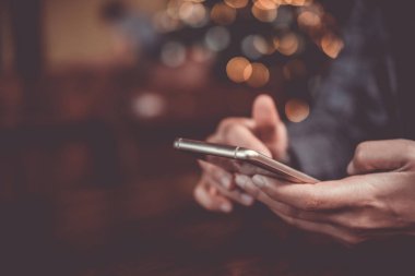Kafe arka planında akıllı telefon kullanan bir kadın. İş, finans, ticaret hisseleri ve sosyal ağ.