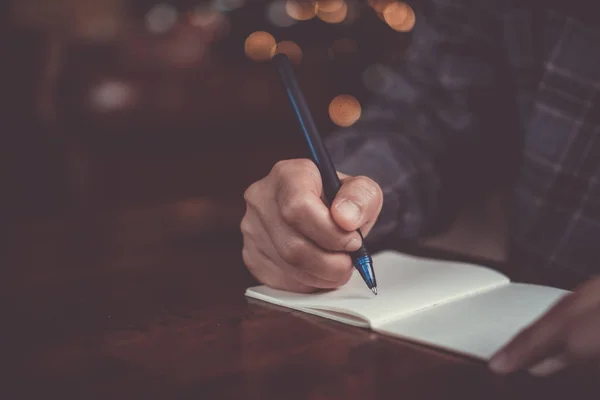 Kvinna hand skriva ner i små vita anteckningar anteckningsbok för att ta en anteckning att inte glömma eller att göra lista plan. — Stockfoto