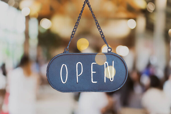 A business sign that says Open on cafe or restaurant hang on door at entrance. Vintage color tone style.