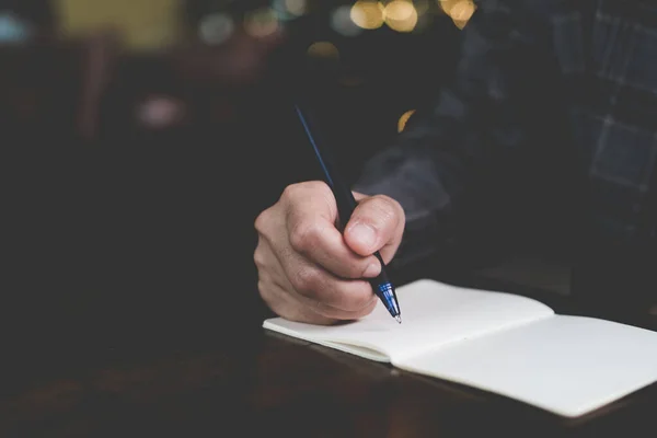 Mujer mano escribiendo en pequeño cuaderno de notas blanco para tomar una nota para no olvidar o hacer plan de lista . — Foto de Stock