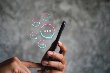 Kadınlar akıllı telefon daktiloyla yazı yazıp sohbet ediyorlar. Sohbet kutusu simgeleri ortaya çıkıyor. Sosyal medya teknolojisi kavramı.