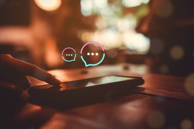 Kadınlar akıllı telefon daktiloyla yazı yazıp sohbet ediyorlar. Sohbet kutusu simgeleri ortaya çıkıyor. Sosyal medya teknolojisi kavramı.
