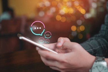 Kadınlar akıllı telefon daktiloyla yazı yazıp sohbet ediyorlar. Sohbet kutusu simgeleri ortaya çıkıyor. Sosyal medya teknolojisi kavramı.