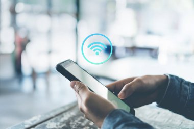 Kafe arka planında wifi simgesi olan akıllı telefon kullanan bir kadın..